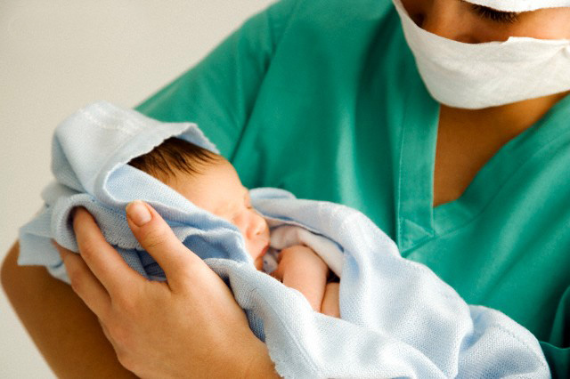 A medical practitioner holding a newborn baby