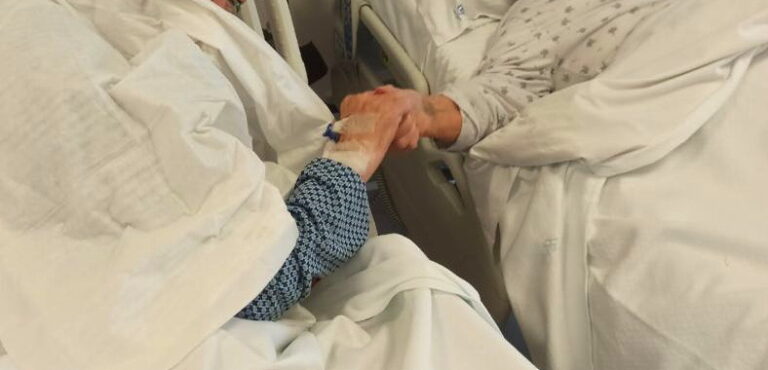Due anziani coniugi si tengono per mano nel reparto Covid-19 in cui sono ricoverati, la foto commuove il web