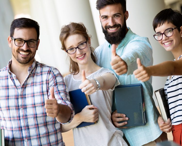 Happy young university students studying with books in library